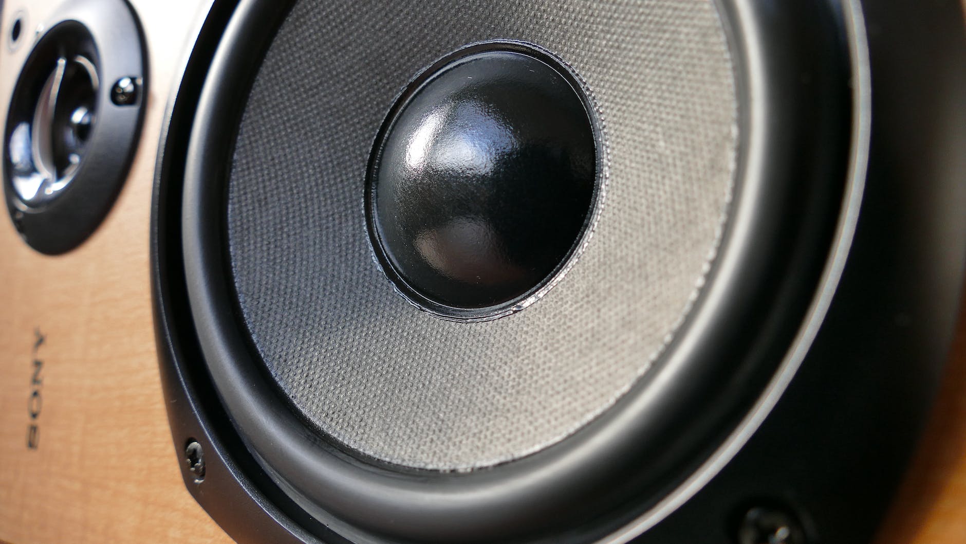 A close up of a Sony loudspeaker in a wooden cabinet laid on its side.