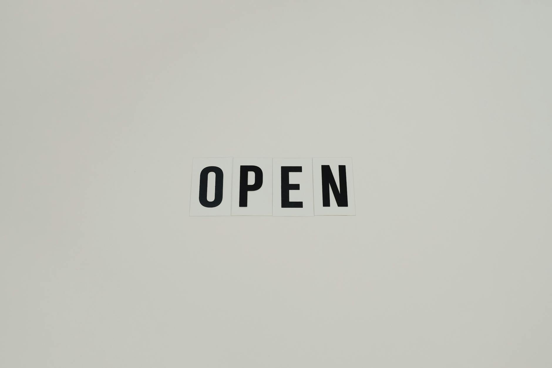 A rectangular white sign with text that says "OPEN"